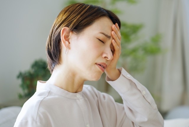 頭痛で頭をおさえる女性